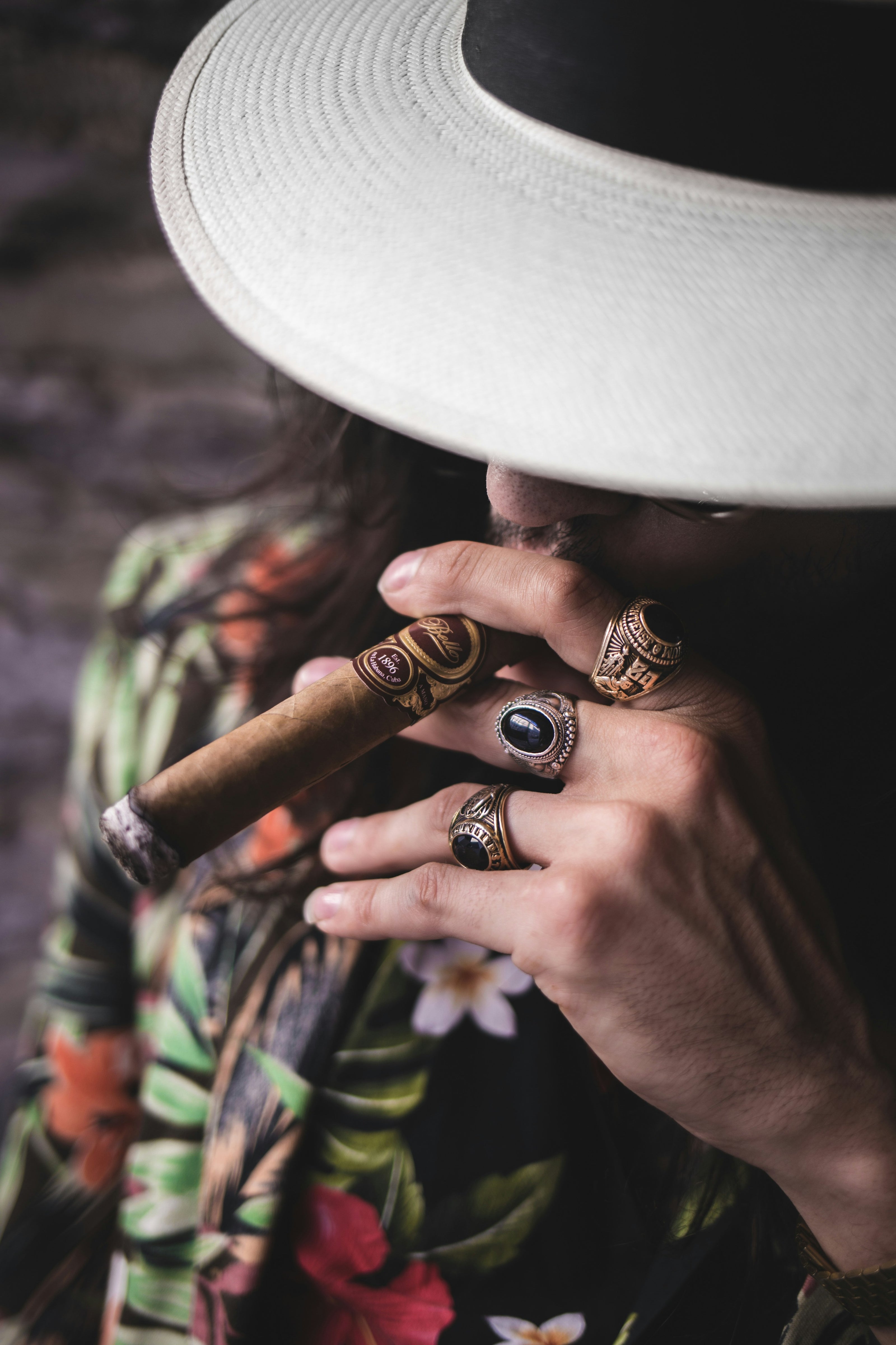 A man smoking a hand-rolled cigar  wearing a hat top view